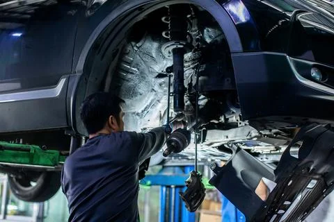Selective focus to Mechanic Inspecting Underbody Suspension and Axle of Car.. Stock Photos