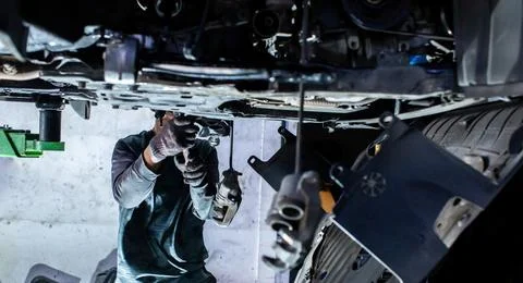 Selective focus to mechanic Working Underneath Vehicle Suspension and Chass.. Stock Photos