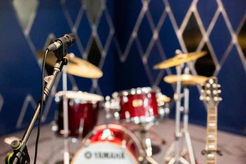 Selective focus to microphone with blurry rock band, drum set. Stockfoto's