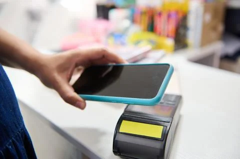 Selective focus on mobile phone in the hand of a customer paying via NFC tech Stock Photos