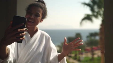 Selective focus on mobile phone of young woman in bathrobe communicating with Stock Footage 149435379