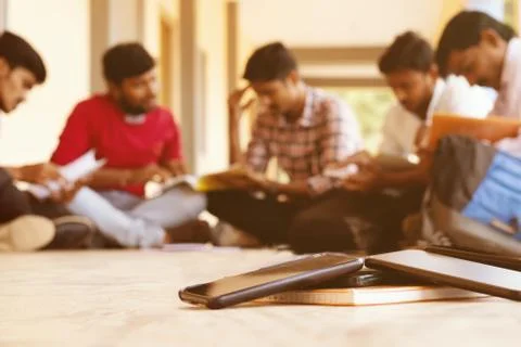 Selective focus on mobiles, group of students busy in reading by avoiding Stock Photos