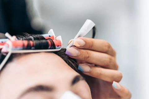 Selective focus on the modern painted nails of a hairdresser while working Stock Photos