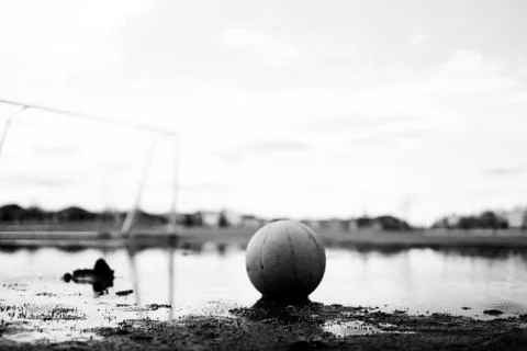 Selective focus on mud in front of a basketball sitting in a mudpuddle of water Stock Photos