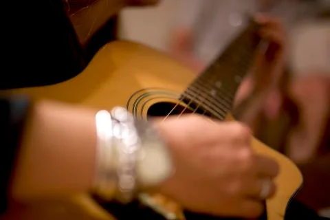 Selective focus with nice bokeh of a young woman playing the guitar Stock Photos