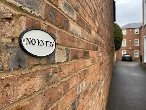Selective focus on no entry sign on brick wall, residential building on backg Stock Photos