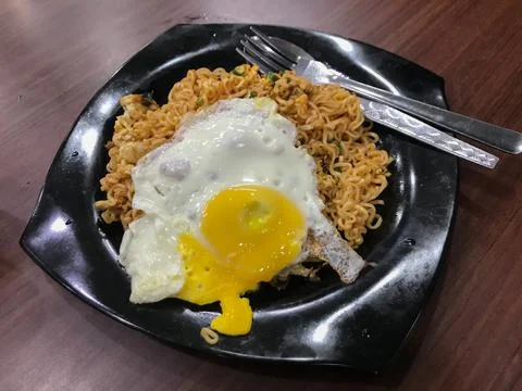 Selective focus with noise effect of friend noodles with fried egg on black p Stock Photos