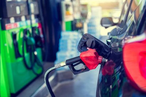 Selective focus to old red fuel nozzle with blurry fuel dispenser in gas stat Foto stock