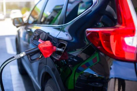 Selective focus to old red fuel nozzle in gas station. Stock Photos