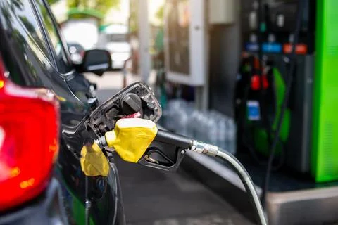 Selective focus to old red fuel nozzle with blurry fuel dispenser in gas stat Stock Photos