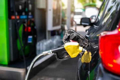 Selective focus to old red fuel nozzle with blurry fuel dispenser in gas stat Foto stock