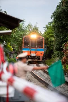 Selective focus to passenger train with blurry Thai railway officer holding.. Stock Photos
