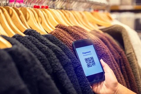 Selective focus to payment QR code tag on smartphone with blurry many clothes Foto stock