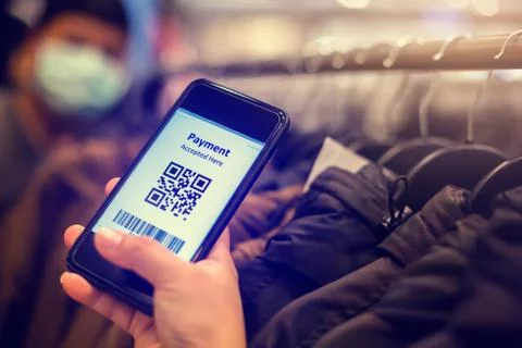 Selective focus to payment QR code tag on smartphone with blurry many clothes Stock Photos