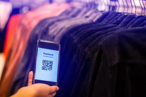 Selective focus to payment QR code tag on smartphone with blurry many clothes Foto stock