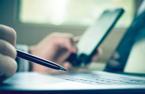 Selective focus pens hold in hand on background laptop keyboard and businessman  Stock Photos