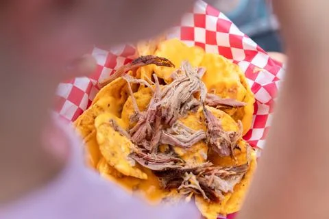 Selective focus of pork meat nachos in girls lap at a street fair Stock Photos
