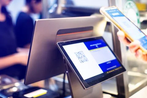 Selective focus to POS Machine with blurry customer scan QR code to payment.. Stockfoto's