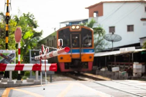 Selective focus to railroad crossing gate with blurry passenger train appro.. Stock Photos
