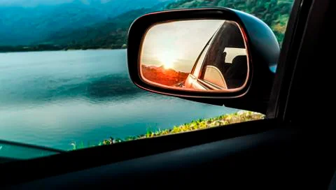 Selective focus Rear view mirror of a car reflecting sunset. Sunset in the re Stock Photos