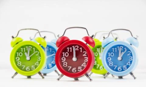 In selective focus of the red alarm clock put at the middle of green and blue Foto stock