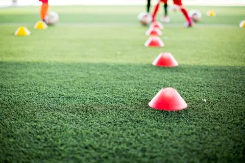 Selective focus to red cone marker is soccer training equipment on green arti Фото