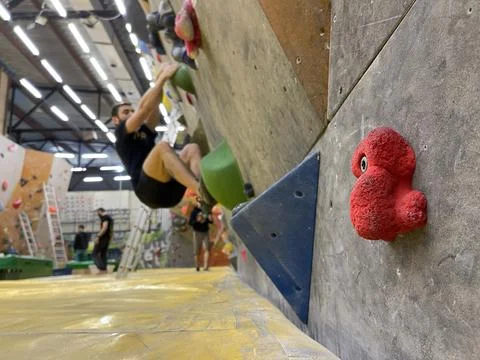 Selective focus on red handhold on a wall at bouldering gym, unrecognizable m Stock Photos