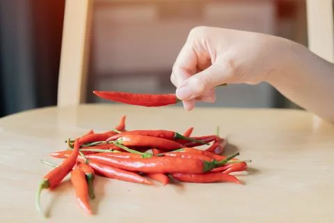 Selective focus of red hot chili pepper in hand over of chili peppers on wo.. Stock Photos