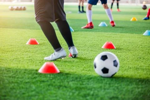 Selective focus to red marker cones with blurry soccer ball and kid soccer pl Stock Photos
