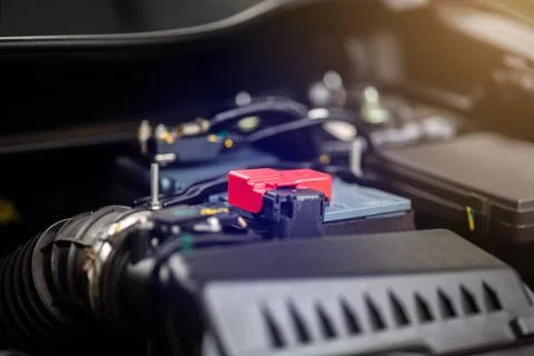 Selective focus to red positive pole of battery in yellow car. Stock Photos