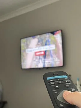 Selective focus on remote control switching channels on the tv Stock Photos