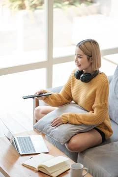 Selective focus on remote of Portrait beautiful young asian woman use remote on Stock Photos
