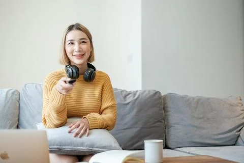 Selective focus on remote of Portrait beautiful young asian woman use remote on Stock Photos