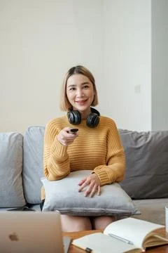 Selective focus on remote of Portrait beautiful young asian woman use remote on Stock Photos