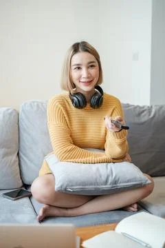 Selective focus on remote of Portrait beautiful young asian woman use remote on Stock Photos