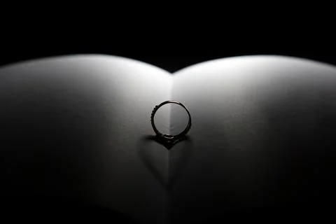 Selective focus on the ring on the open book results in a heart-shaped shadow Foto stock