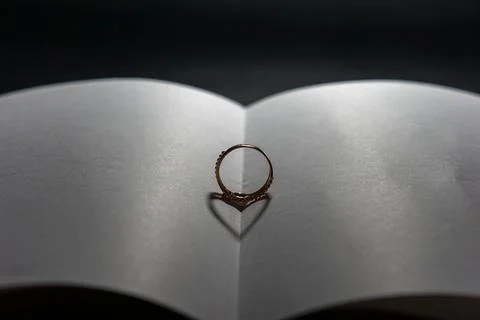 Selective focus on the ring on the open book results in a heart-shaped shadow Foto stock