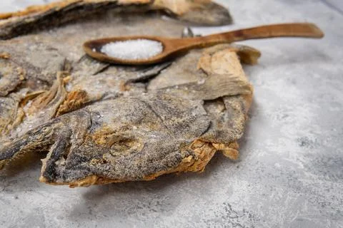 Selective focus of a salted cod head with a wooden spoon with grains of salt out Stock Photos