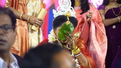 Selective focus shot of bengali bride in red saree and jewellery hiding behind a Stock Footage 125328491