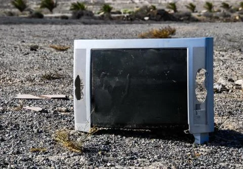 A selective focus shot of a broken screen of a television placed on a rocky s Foto stock