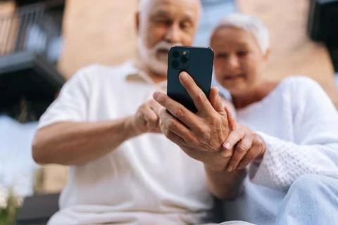 Selective focus shot of elderly married couple using smartphone, exploring apps Fotos Stock
