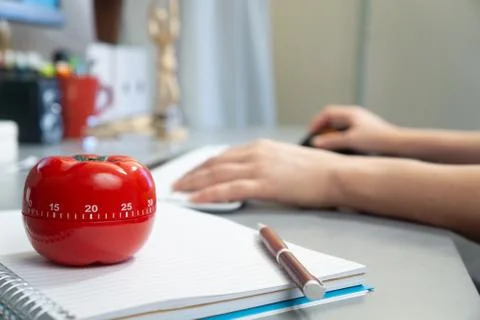 Selective focus shot of a kitchen timer in the form of a tomato on a notebook Stock Photos