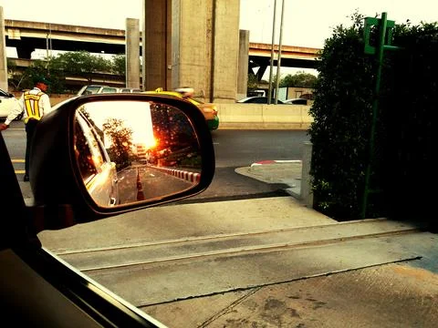 Selective focus at side mirror with cone traffic, building and sunlight flare Stock Photos
