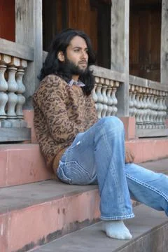 Selective focus side view of a attractive Indian young guy with long hair Stock Photos