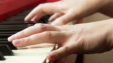 Selective focus side view of a woman's hand playing red the piano Stock Footage 195658196