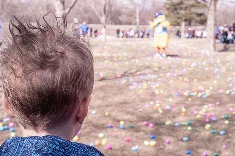 Selective focus on a single child looking out over a field of plastic Easter Stock Photos
