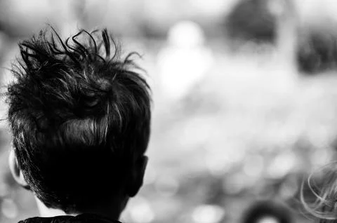 Selective focus on a single child with messy hair sticking up looking forward. Stock Photos