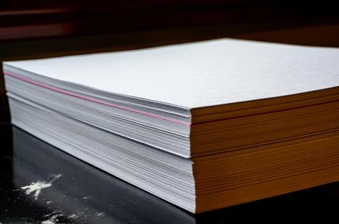 Selective focus on a single colored sheet in a stack of plain white paper Stock Photos