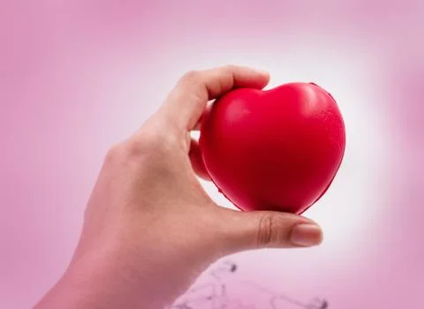 In selective focus of small red heart in human hand,blurry light design backg 库存照片