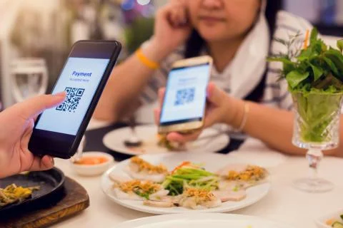 Selective focus to smartphone in hand to scan QR code on tag with blurry food Foto stock